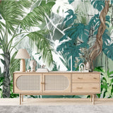 Papier Peint Panoramique Safari dans un salon de style scandinave avec buffet en bois clair et décoration minimaliste. Illustration d'une scène tropicale dense avec des plantes aux grandes feuilles vertes, des lianes brunes et un fond flou en nuances de vert, blanc et gris, montrant une forêt épaisse.