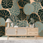 Papier Peint Tropical Chic Exotique dans un salon de style scandinave avec buffet en bois clair et décoration minimaliste. Illustration d'un motif moderne de feuilles tropicales avec des feuilles superposées et des détails de nervures complexes, utilisant une palette de couleurs composée de verts foncés, bleus et ors.