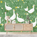 Tapisserie Murale Animaux De La Ferme dans un salon de style scandinave avec buffet en bois clair et décoration minimaliste. Illustration d'un groupe d'oies blanches parcourant une prairie verdoyante remplie de fleurs jaunes et blanches, dans un style de livre pour enfants.