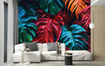 Papier Peint Tropical Coloré dans un intérieur moderne et luxueux avec un grand canapé sectionnel blanc, une table basse en verre, et des touches dorées. Illustration d'un motif vibrant de feuilles tropicales avec de grandes feuilles superposées aux détails minutieux, utilisant des couleurs rouges profonds, verts riches et oranges éclatants.