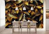 Papier Peint Panoramique Tropical Jungle dans une salle à manger contemporaine avec table en bois naturel, chaises beiges et éclairage suspendu blanc. Illustration de feuilles dorées et brunes aux textures détaillées et aux bords dentelés, étalées de manière aléatoire, avec un contraste intense entre les couleurs chaudes et les zones d'ombre.