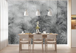 Papier Peint Noir Et Blanc Motif Vegetal dans une salle à manger contemporaine avec table en bois naturel, chaises beiges et éclairage suspendu blanc. Illustration d'une jungle dense et brumeuse avec des plantes tropicales luxuriantes et des oiseaux cachés parmi les branches, réalisée dans une palette de gris et verts foncés.