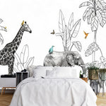 Papier Peint Jungle Bébé Tout Petit dans une chambre à coucher apaisante avec lit blanc, table de chevet moderne, et plantes vertes. Illustration en noir et blanc d'une scène de savane tropicale avec une girafe et trois éléphants marchant parmi des plantes exotiques, des lianes suspendues et des oiseaux colorés perchés sur les animaux et volant autour, dans un style de livre pour enfants.