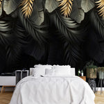 Papier Peint Tropical Fond Noir Exotique dans une chambre à coucher apaisante avec lit blanc, table de chevet moderne, et plantes vertes. Motif d'illustration de feuilles tropicales dorées et noires superposées, sur un fond noir, dans un style moderne et élégant.