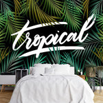 Papier Peint Chambre Tropical dans une chambre à coucher apaisante avec lit blanc, table de chevet moderne, et plantes vertes. Illustration d'une scène tropicale avec des feuilles de palmier vertes et dorées sur un fond noir, avec le mot "tropical" écrit en blanc au centre.