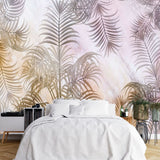 Papier Peint Mural Tropical dans une chambre à coucher apaisante avec lit blanc, table de chevet moderne, et plantes vertes. Illustration de feuilles de palmier stylisées en nuances de rose, beige, gris, et blanc sur un fond abstrait pastel, créant une atmosphère apaisante et douce.