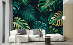 Tapisserie Adhesive Jungle dans un intérieur moderne et luxueux avec un grand canapé sectionnel blanc, une table basse en verre, et des touches dorées. Illustration de grandes feuilles de monstera tropicales dans une forêt dense, présentant diverses tailles et trous, équilibrées par d'autres feuillages exotiques luxuriants dans une palette de verts foncés et de touches de jaune.