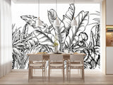 Papier Peint Tropical Fond Blanc Exotique dans une salle à manger contemporaine avec table en bois naturel, chaises beiges et éclairage suspendu blanc. Illustration d'un motif détaillé de feuilles tropicales avec de grandes feuilles superposées et un travail de lignes minutieux, réalisée dans un style noir et blanc.