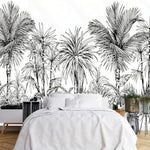 Papier Peint Jungle Tropical Noir Et Blanc Big Panoramique dans une chambre à coucher apaisante avec lit blanc, table de chevet moderne, et plantes vertes. Illustration en gravure noir et blanc de palmiers et une végétation luxuriante tropicale.