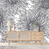 Papier Peint Vegetal Noir Et Blanc dans un salon de style scandinave avec buffet en bois clair et décoration minimaliste. Illustration de motifs floraux stylisés en noir et blanc avec des fleurs exotiques aux pétales allongés, dessinées de manière symétrique en style de dessin au trait.