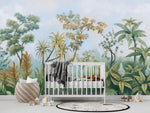 Tapisserie Panoramique Paysage Jungle dans une chambre de bébé moderne et minimaliste avec des murs blancs et un sol foncé, un berceau blanc, une couverture grise à pompons, des peluches, des jouets en bois et un tapis à motif noir et blanc. Illustration d'une scène tropicale avec divers arbres et plantes exotiques sous un ciel légèrement nuageux, réalisée dans un style de peinture botanique classique.