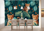 Papier Peint Animaux De La Foret Tropicale dans une salle à manger contemporaine avec table en bois naturel, chaises beiges et éclairage suspendu blanc. Illustration de trois guépards, deux adultes et un jeune, dans une jungle dense avec des feuillages exotiques et des papillons orange.