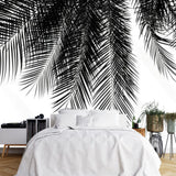 Tapisserie Tropicale Noir Et Blanc Exotique dans une chambre à coucher apaisante avec lit blanc, table de chevet moderne, et plantes vertes. Illustration minimaliste de feuilles de palmier en noir et blanc sur fond clair, en contre-plongée.