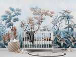 Tapisserie Murale Panoramique Jungle dans une chambre de bébé moderne et minimaliste avec des murs blancs et un sol foncé, un berceau blanc, une couverture grise à pompons, des peluches, des jouets en bois et un tapis à motif noir et blanc. Illustration d'une jungle tropicale avec des palmiers, des fougères et des lianes, dans une palette de couleurs bleu pastel, brun doux et tons verts, créant une atmosphère apaisante et naturelle.