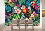 Papier Peint Jungle Perroquet Tropical dans une salle à manger contemporaine avec table en bois naturel, chaises beiges et éclairage suspendu blanc. Illustration de trois perroquets colorés perchés sur des branches entourées de feuillage tropical luxuriant et de fleurs colorées.