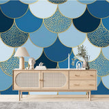 Papier Peint Style Ecaille De Poisson dans un salon de style scandinave avec buffet en bois clair et décoration minimaliste. Illustration d'un motif répétitif en forme d'écailles de poisson, avec des teintes variées de bleu et des détails en or, disposé de manière symétrique dans un style géométrique élégant.