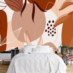 Papier Peint Panoramique Jungle Terracotta dans une chambre à coucher apaisante avec lit blanc, table de chevet moderne, et plantes vertes. Illustration abstraite avec formes géométriques et motifs de feuilles stylisés dans des tons de marron, beige, et terre cuite.