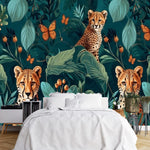 Papier Peint Animaux De La Foret Tropicale dans une chambre à coucher apaisante avec lit blanc, table de chevet moderne, et plantes vertes. Illustration de trois guépards, deux adultes et un jeune, dans une jungle dense avec des feuillages exotiques et des papillons orange.