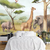 Papier Peint Panoramique Elephants Et Girafes dans une chambre à coucher apaisante avec lit blanc, table de chevet moderne, et plantes vertes. Illustration d'une savane africaine avec une girafe, un rhinocéros, deux éléphants, des acacias, des baobabs, et deux oiseaux exotiques en vol, réalisée dans un style aquarelle réaliste.