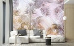 Papier Peint Mural Tropical dans un intérieur moderne et luxueux avec un grand canapé sectionnel blanc, une table basse en verre, et des touches dorées. Illustration de feuilles de palmier stylisées en nuances de rose, beige, gris, et blanc sur un fond abstrait pastel, créant une atmosphère apaisante et douce.