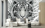 Papier Peint Noir Blanc Jungle Et Animaux dans un intérieur moderne et luxueux avec un grand canapé sectionnel blanc, une table basse en verre, et des touches dorées. Illustration en noir et blanc d'un tigre au milieu de la jungle entouré de feuilles tropicales détaillées.