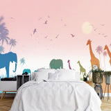 Papier Peint Safari Enfant dans une chambre à coucher apaisante avec lit blanc, table de chevet moderne, et plantes vertes. Illustration d'une savane tropicale au coucher du soleil avec des silhouettes d'animaux tels que des éléphants, des girafes et des oiseaux, sur fond d'arbres et de palmiers, éclairée de nuances pastel.