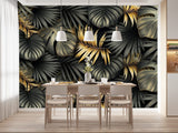 Papier Peint Tropical Noir Doré dans une salle à manger contemporaine avec table en bois naturel, chaises beiges et éclairage suspendu blanc. Illustration d'un motif luxueux de feuilles tropicales avec de grandes feuilles superposées et des détails minutieux, utilisant des couleurs noir et or avec des textures contrastantes sur un fond sombre.