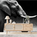 Papier Peint Safari Jungle dans un salon de style scandinave avec buffet en bois clair et décoration minimaliste. Illustration d'un éléphant majestueux marchant sur un terrain herbeux au crépuscule, avec un arrière-plan légèrement flou.