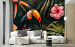 Papier Peint Panoramique Tropical Feuille Fleur Toucan dans un intérieur moderne et luxueux avec un grand canapé sectionnel blanc, une table basse en verre, et des touches dorées. Illustration d'un toucan coloré perché sur une branche au milieu de feuillages tropicaux verts épais, entouré de fleurs exotiques telles que des hibiscus roses et des fleurs de frangipanier jaunes.