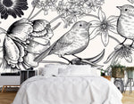 Papier Peint Tropical Noir Et Blanc Oiseaux dans une chambre à coucher apaisante avec lit blanc, table de chevet moderne, et plantes vertes. Illustration d'oiseaux perchés parmi diverses fleurs incluant des pivoines, gerberas et jacintes, réalisée en style gravure sur bois en noir et blanc.