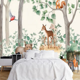 Papier Peint Panoramique Foret Enfant dans une chambre à coucher apaisante avec lit blanc, table de chevet moderne, et plantes vertes. Illustration d'une scène de forêt avec des animaux mignons, incluant un faon, un ours, un renard, un écureuil, un lapin, un hérisson et des oiseaux, entourés d'arbres et de buissons, dans un style aquarelle doux et enfantin.