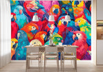 Tapisserie Panoramique Oiseaux dans une salle à manger contemporaine avec table en bois naturel, chaises beiges et éclairage suspendu blanc. Illustration d'un groupe dense de perroquets aux plumes colorées dans une variété de teintes vibrantes, incluant rouge, bleu, vert, jaune et violet, illustrés dans un style artistique réaliste moderne.