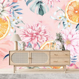 Papier Peint Tropical Cuisine dans un salon de style scandinave avec buffet en bois clair et décoration minimaliste. Illustration d'un motif floral aquarelle, avec des fleurs roses et blanches éclatantes, des tranches d'orange, et des feuilles vert foncé sur un fond rose pastel.