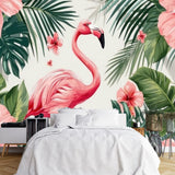 Papier Peint Panoramique Animaux De La Foret Exotique dans une chambre à coucher apaisante avec lit blanc, table de chevet moderne, et plantes vertes. Illustration d'une scène tropicale avec un flamant rose au centre, entouré de grandes feuilles vertes et de fleurs d'hibiscus rose vif, avec des papillons roses volant autour.