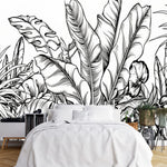 Papier Peint Tropical Fond Blanc Exotique dans une chambre à coucher apaisante avec lit blanc, table de chevet moderne, et plantes vertes. Illustration d'un motif détaillé de feuilles tropicales avec de grandes feuilles superposées et un travail de lignes minutieux, réalisée dans un style noir et blanc.