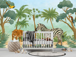 Papier Peint Panoramique Jungle Enfant dans une chambre de bébé moderne et minimaliste avec des murs blancs et un sol foncé, un berceau blanc, une couverture grise à pompons, des peluches, des jouets en bois et un tapis à motif noir et blanc. Illustration d'une scène tropicale de savane avec un léopard et un zèbre au premier plan entourés de divers arbres tropicaux et palmiers, et des oiseaux colorés perchés sur les branches.