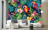 Papier Peint Jungle Perroquet Tropical dans un intérieur moderne et luxueux avec un grand canapé sectionnel blanc, une table basse en verre, et des touches dorées. Illustration de trois perroquets colorés perchés sur des branches entourées de feuillage tropical luxuriant et de fleurs colorées.