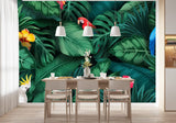 Tapisserie Jungle Oiseau dans une salle à manger contemporaine avec table en bois naturel, chaises beiges et éclairage suspendu blanc. Illustration d'une jungle tropicale dense avec des feuilles vertes luxuriantes, des perroquets colorés, un cacatoès blanc, des toucans, et des fleurs tropicales vives comme des hibiscus rouge et jaune.